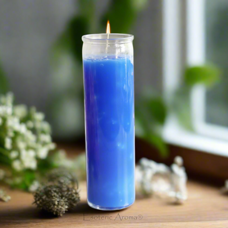 Blue candle with a flame on a wooden surface with blurred greenery in the background