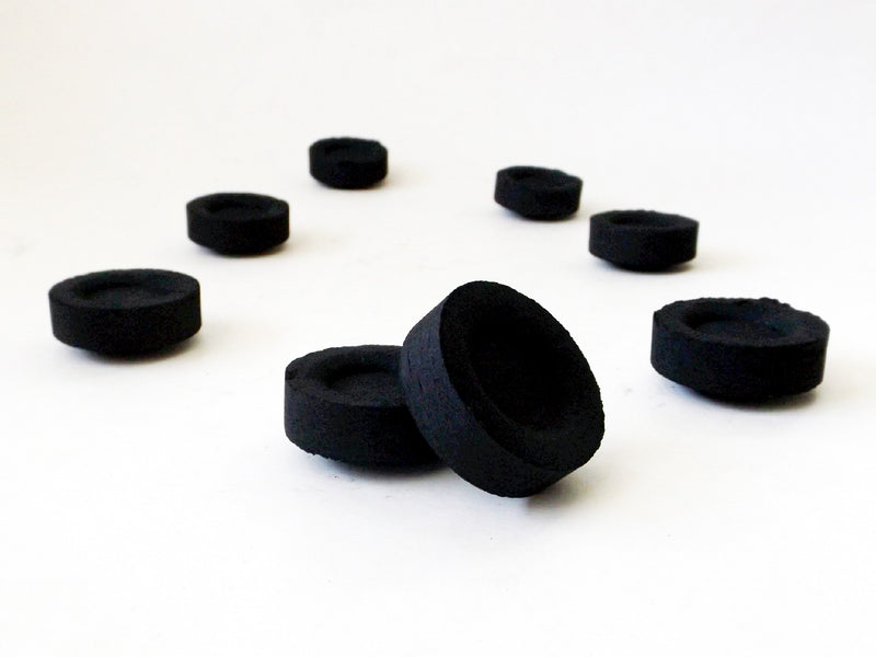 Black charcoal discs on white background