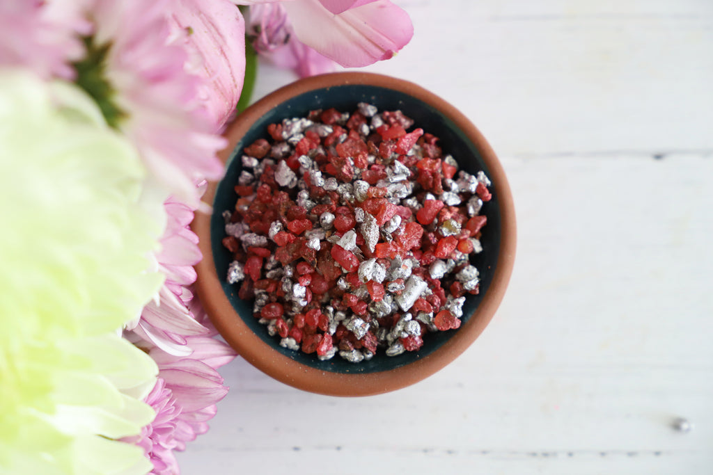 Bowl of resin incense grains on a white background with flowers