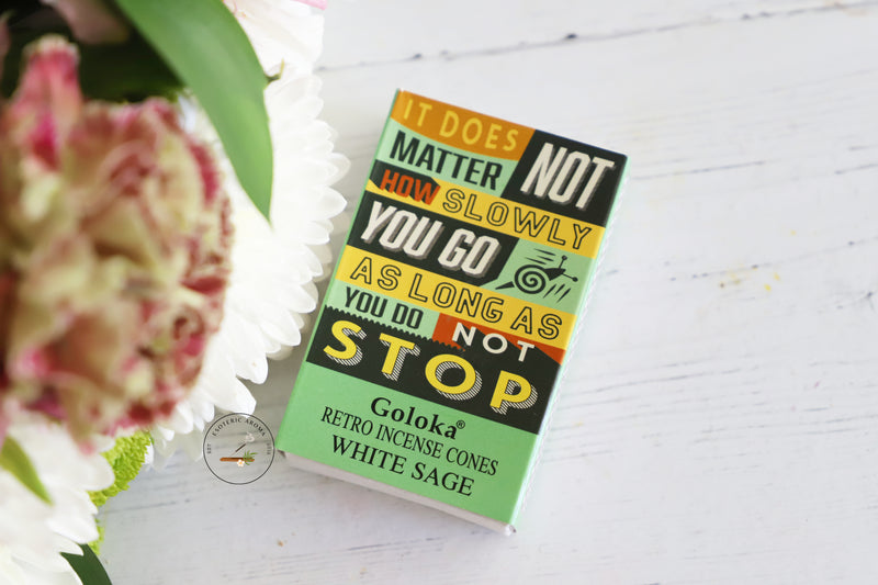 Goloka retro incense cones packaging with motivational quote on a white surface with flowers.