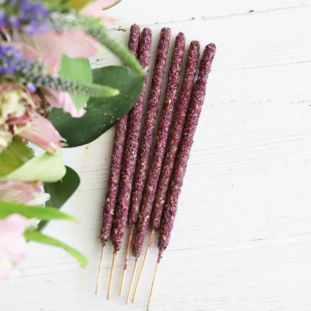 Incense sticks on a white background with fresh flowers on the side.