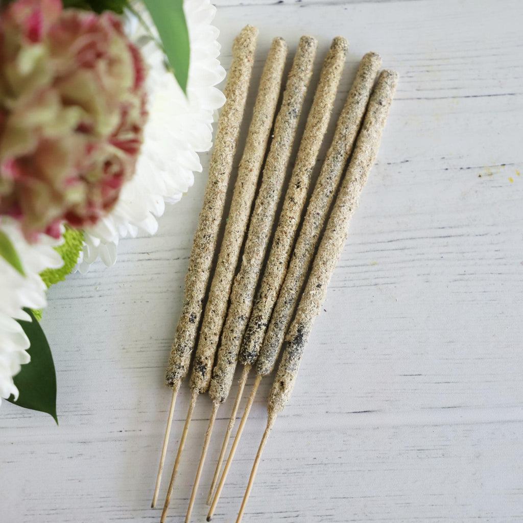 Incense sticks on a white background with fresh flowers on the side.