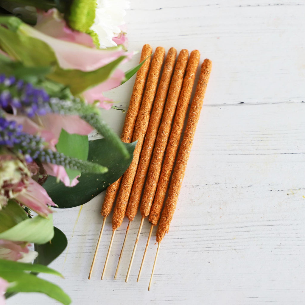 Incense sticks on white background with fresh flowers on the side.