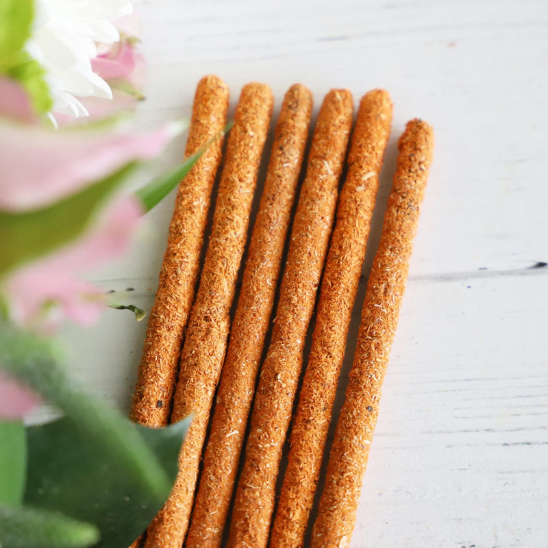 Incense sticks on white background with fresh flowers on the side.
