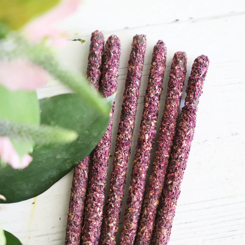 Incense sticks on a white background with fresh flowers on the side.
