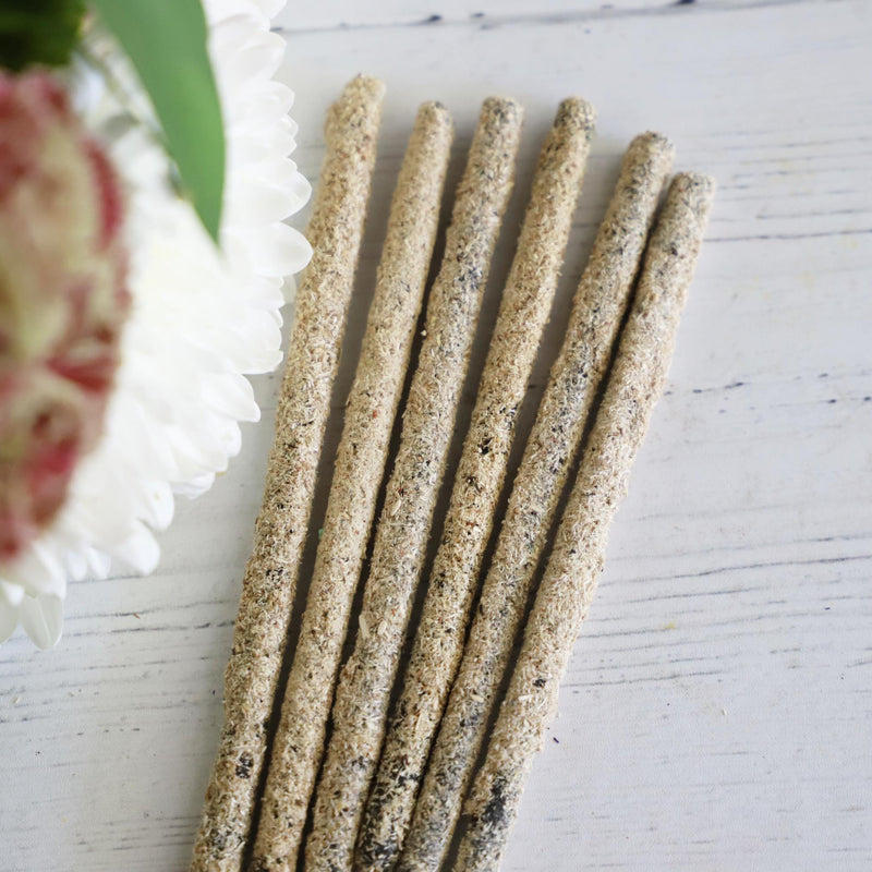 Incense sticks on a white background with fresh flowers on the side.