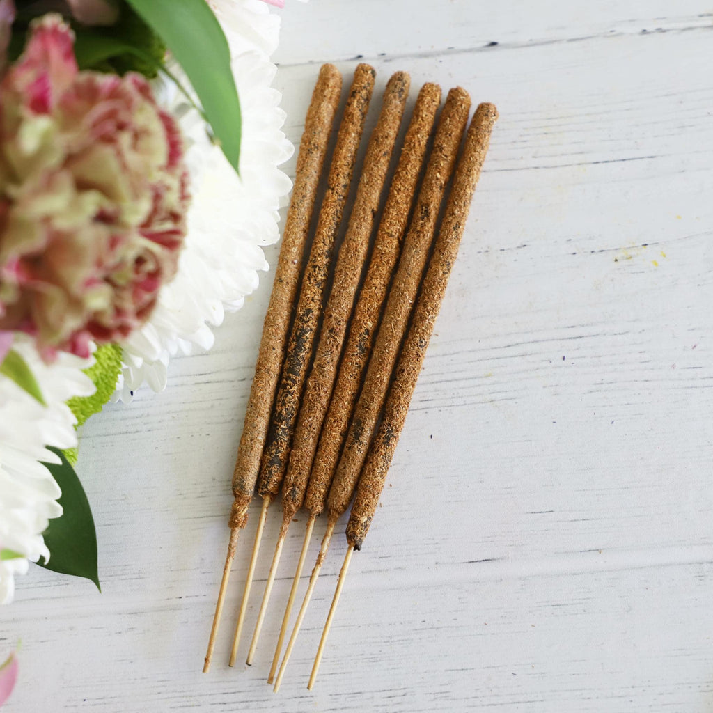 Incense sticks on white background with fresh flowers on the side.