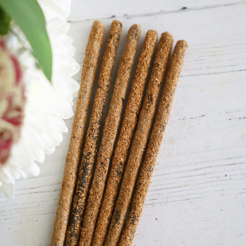 Incense sticks on white background with fresh flowers on the side.