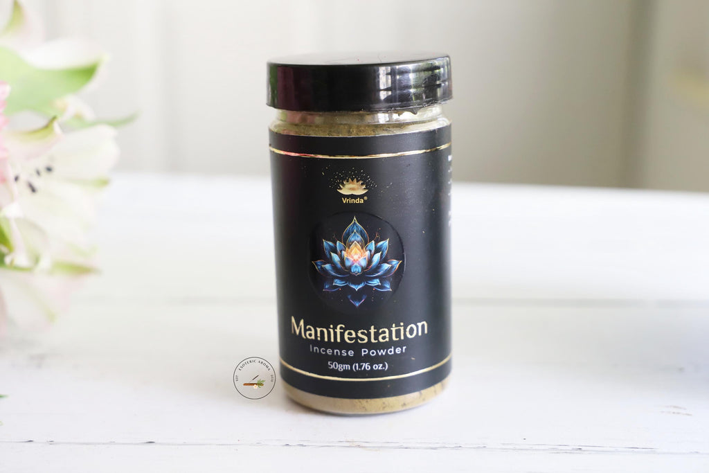 Vrinda Manifestation incense powder jar on a white table with a white background and fresh white flowers next to it.