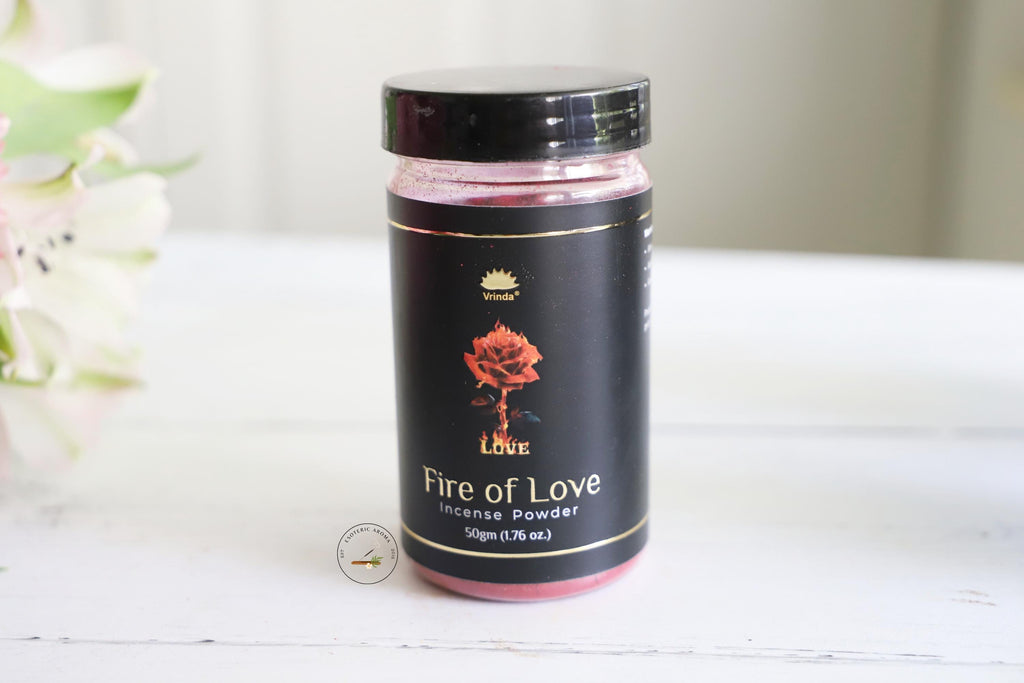 Vrinda Fire of Love incense powder jar on a white table with a white background and white flowers next to it.