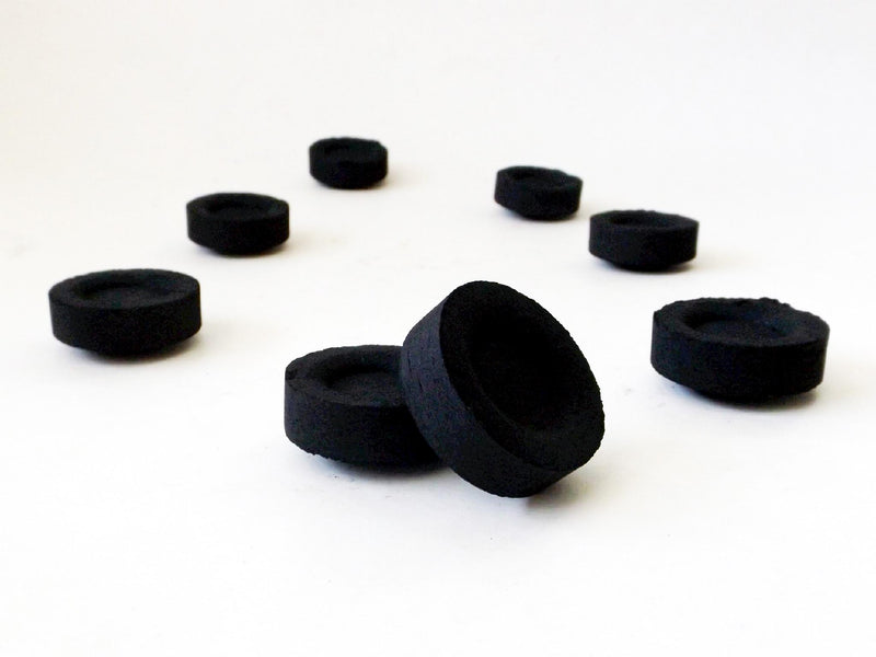 Black charcoal discs on white background