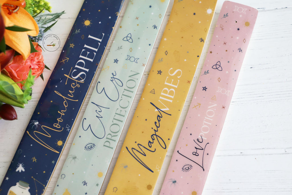 4 colorful celestial themed incense holders on white background with colorful fresh flowers next to them.