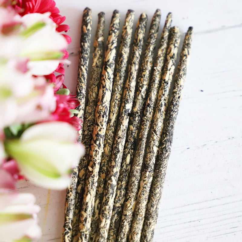 Incense sticks on white background with red and white fresh flowers next to it.