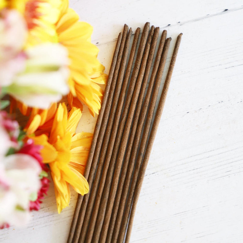 Incense sticks on a white background with colorful fresh flowers.