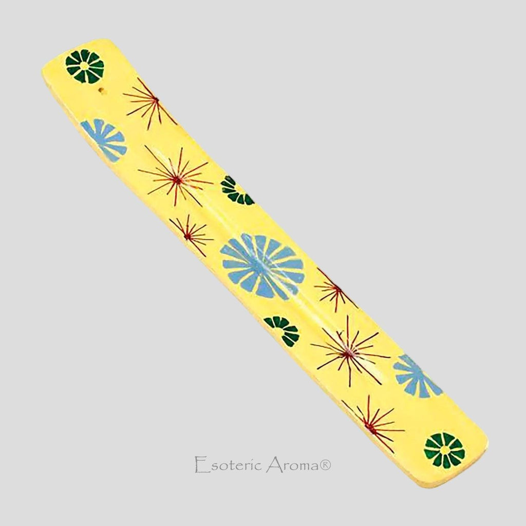 Yellow incense holder with red, blue, green patterns on a grey background.