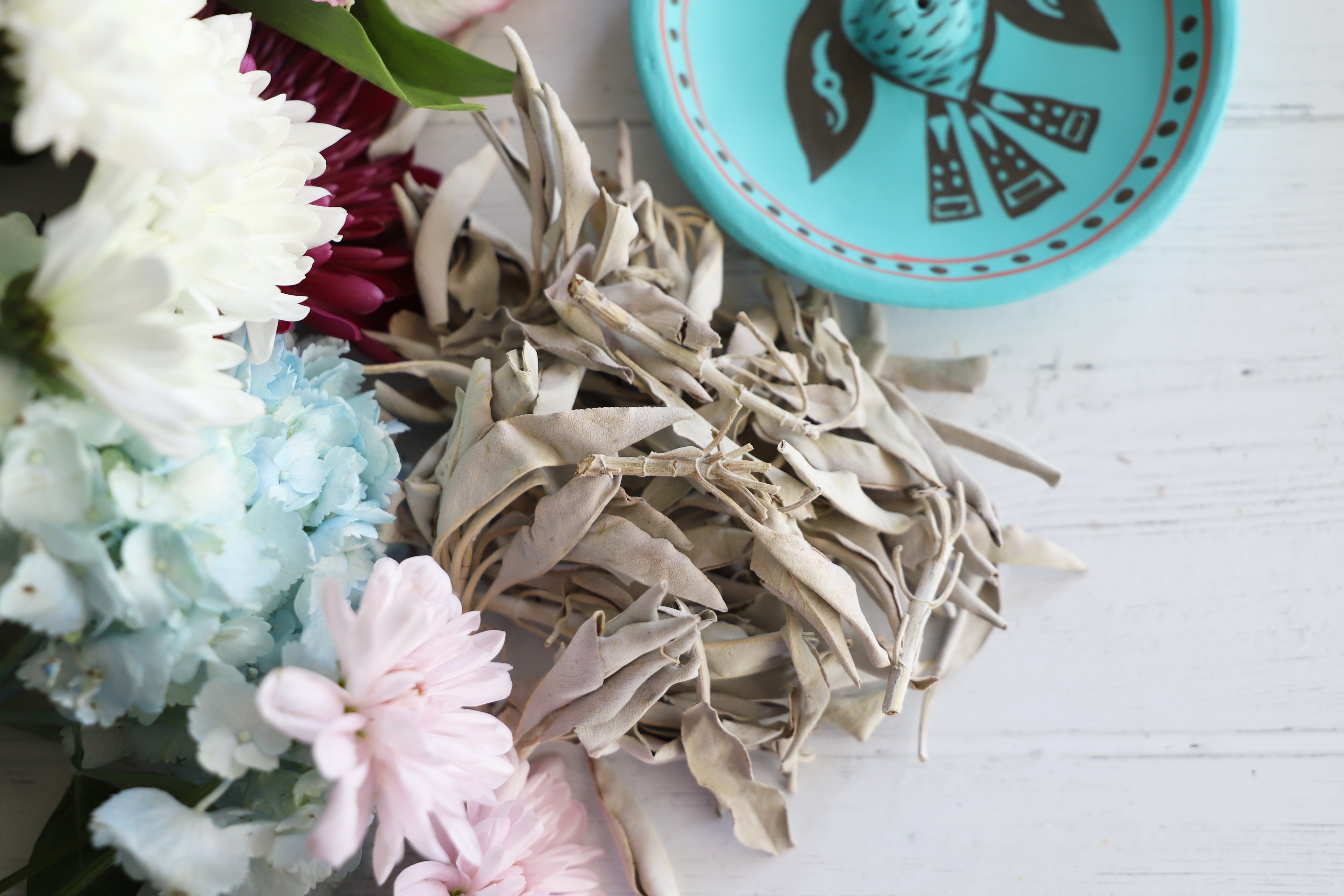 Loose California white sage bundles in a wooden bowl on a boho table