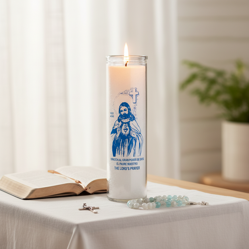 Candle with a religious design on a table with an open book and rosary.