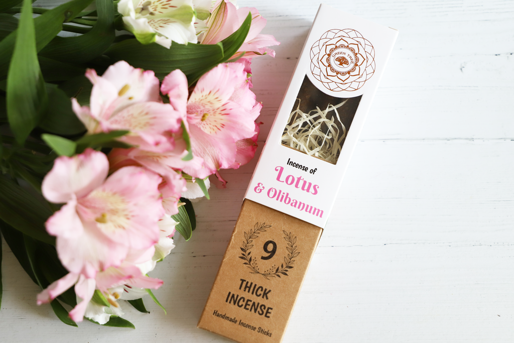 Green Tree Incense of Lotus & Olibanum incense package on white table with pink flowers and green leaves.