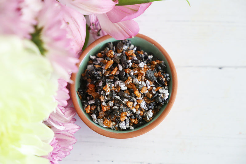 Small bowl of resin incense with pink flowers on a white surface