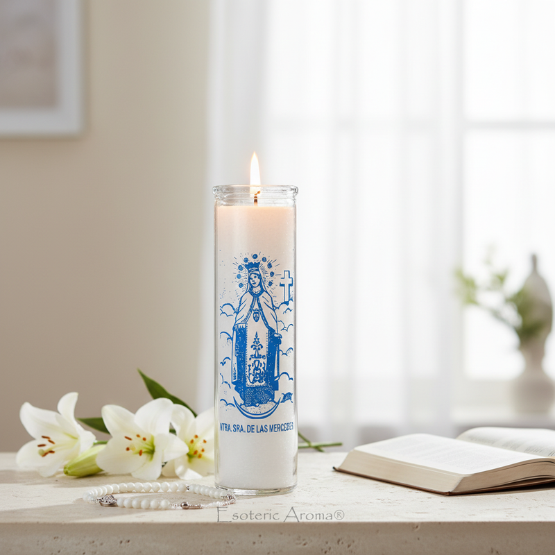 Candle with a blue religious illustration on a table with flowers and an open book.