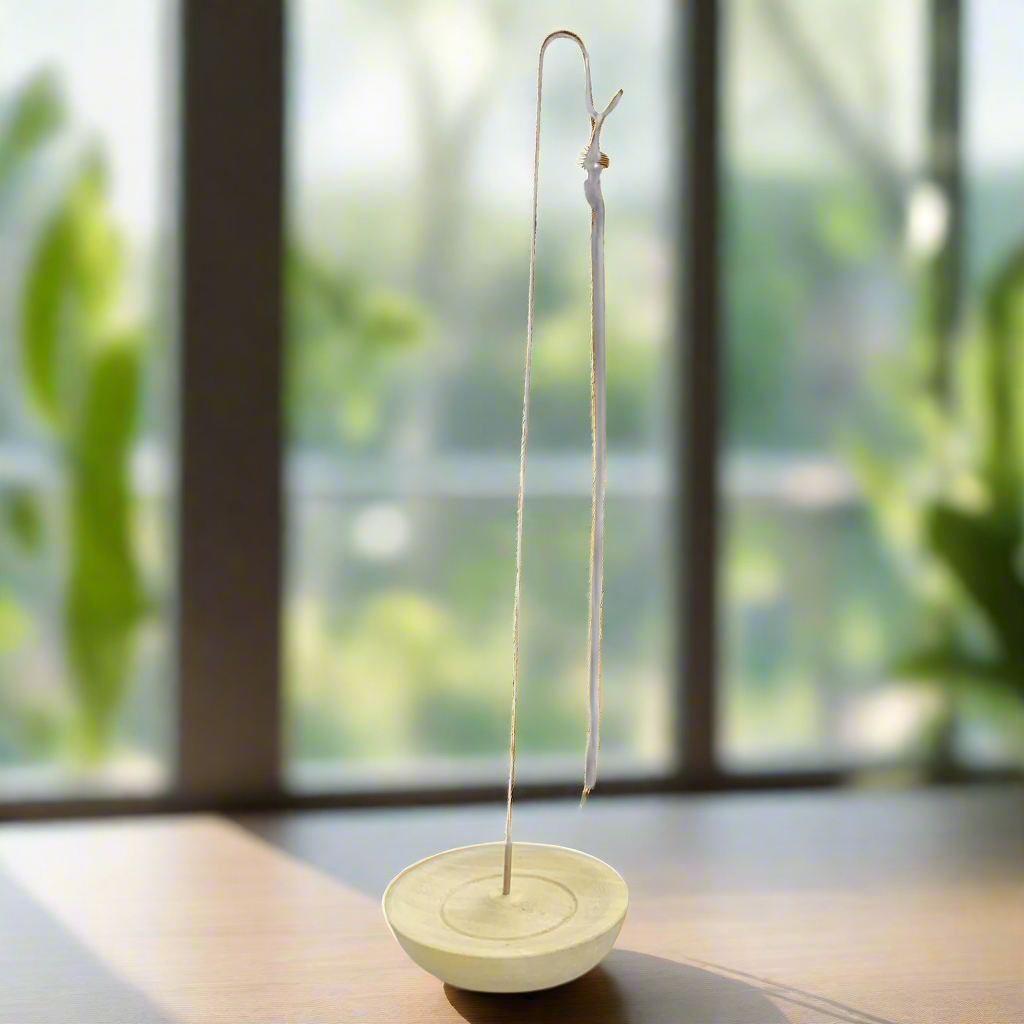 Rope incense hanging from a metal rod in a wooden base on a white background.